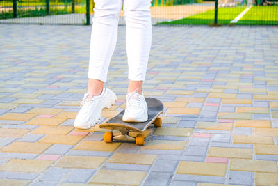 Low section of woman standing on footpath