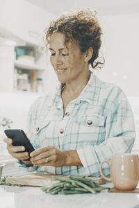 Young man using mobile phone while sitting on table