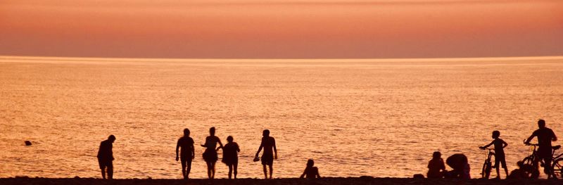 Silhouette people at beach during sunset