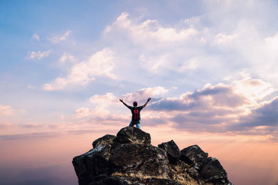 View of man standing on rock against sky