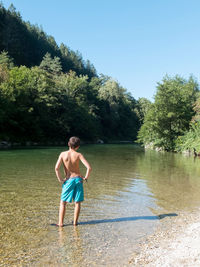 Full length of shirtless boy standing in lake