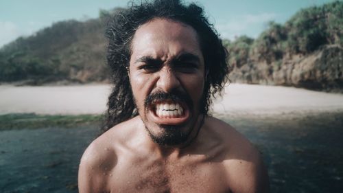 Portrait of shirtless man clenching teeth