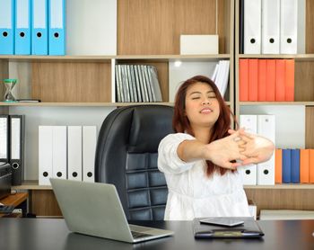 Full length of woman using phone while sitting on table