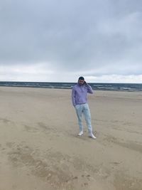 Full length of man standing on beach against sky