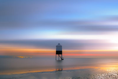 Scenic view of sea with lifeguard hut against sky during sunset