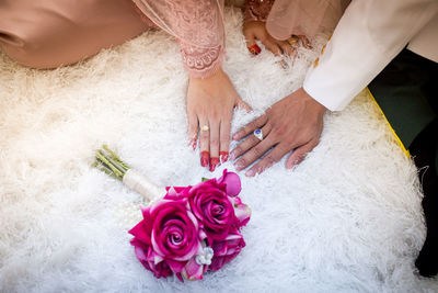 Cropped hands of wedding couple touching fur