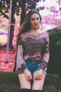 Portrait of beautiful young woman sitting on rock