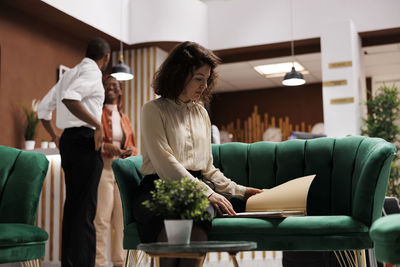 Side view of woman sitting on sofa at home