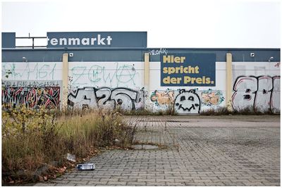 Graffiti on wall by footpath against sky