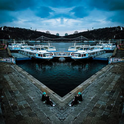 Boats moored at harbor against sky