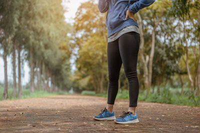 Low section of woman standing on road against forest