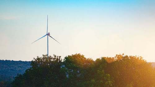 Low angle view of wind turbines against sky during sunset