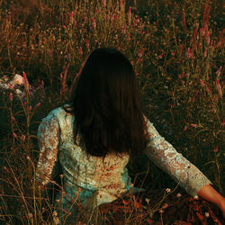 Rear view of woman sitting on field