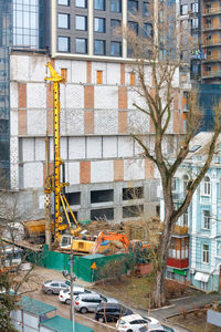 A heavy excavator along with a drilling rig mechanism works at a construction site.