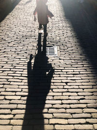 Shadow of woman walking on footpath