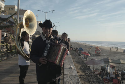 Group of people at beach against sky
