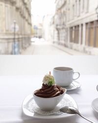 Close-up of coffee with dessert served on table by window