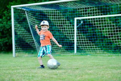 Full length of boy playing soccer on court