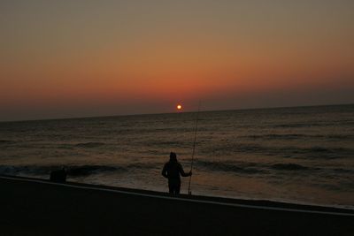 Silhouette of people on beach at sunset