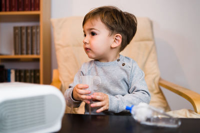 Cute boy holding respiratory mask at home