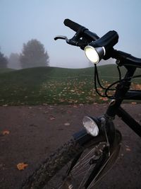 Bicycle on road by field against sky