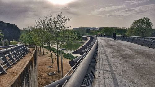 Empty footpath by canal against sky