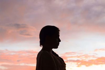 Side view of silhouette of woman against orange sky