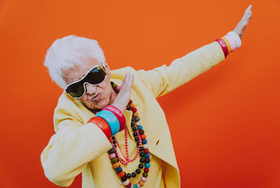 Portrait of senior woman gesturing against red background