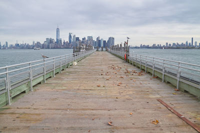Pier of liberty island over sea against lower manhattan 