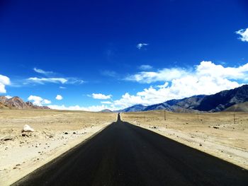 Road amidst desert against blue sky