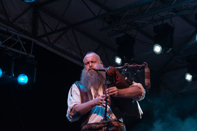 Low angle view of man looking at illuminated lights at night