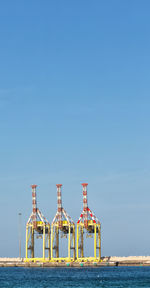 Built structure by sea against clear blue sky