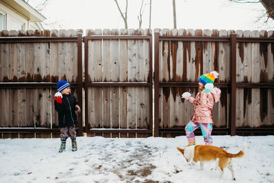 Young brother and sister having a snow ball fight in winter