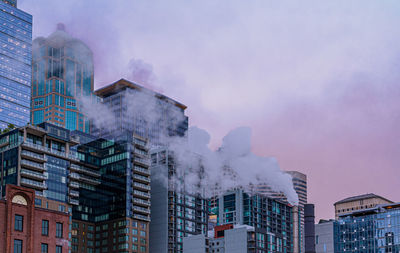 Low angle view of smoke stack and buildings in city