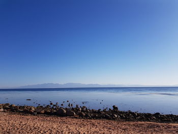 Scenic view of beach against clear blue sky