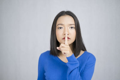 Portrait of beautiful young woman standing against white background