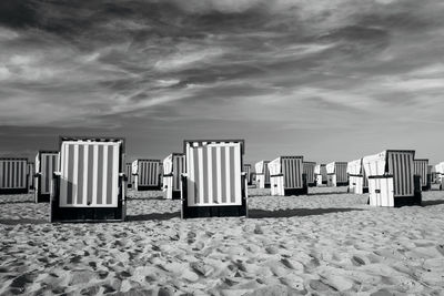 Deck chairs on beach against sky