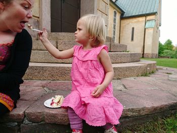 Portrait of cute girl feeding cake to woman