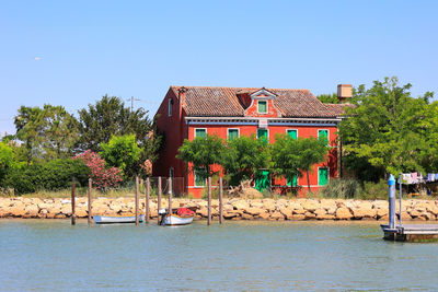 Houses by sea against clear blue sky