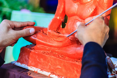 Cropped image of sculptor painting statue