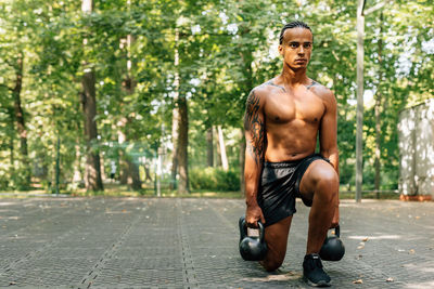 Full length portrait of shirtless man in park