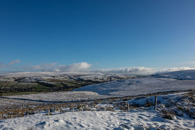 Scenic view of snow covered landscape against blue sky