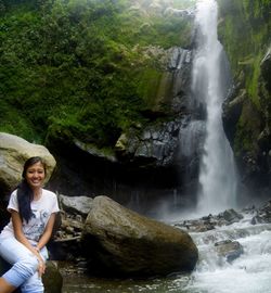 Woman standing on rock against waterfall