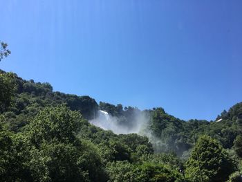 Scenic view of waterfall against clear blue sky