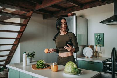 Woman standing by potted plant at home