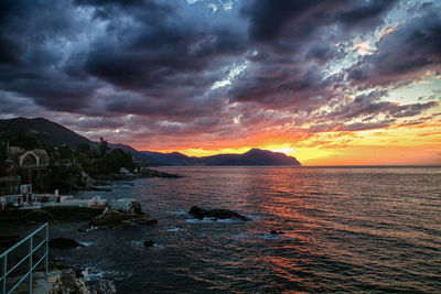 Scenic view of sea against dramatic sky during sunset