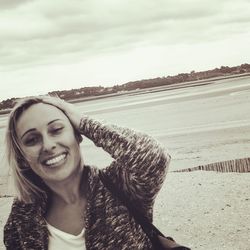 Portrait of smiling young woman against sky