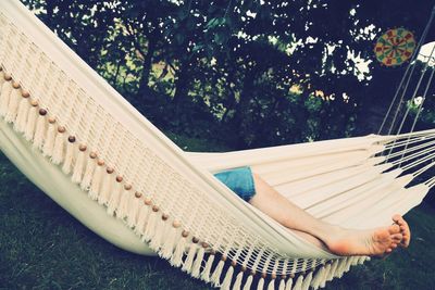 Low section of person relaxing in hammock against trees