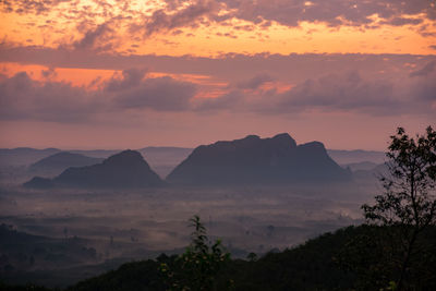 Scenic view of silhouette mountains against orange sky