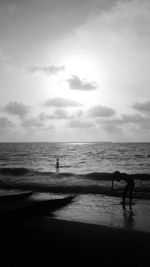 Silhouette people standing on beach against sky during sunset